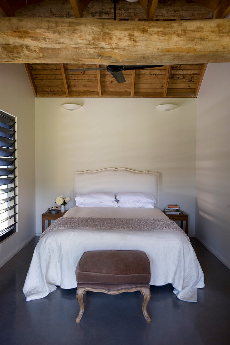 Doppelbett in schlichtem Schlafzimmer mit Holzbalken