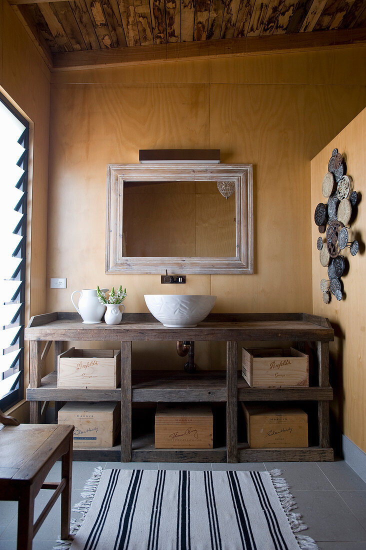 Rustic washstand with wooden boxes on shelves and countertop sink in bathroom