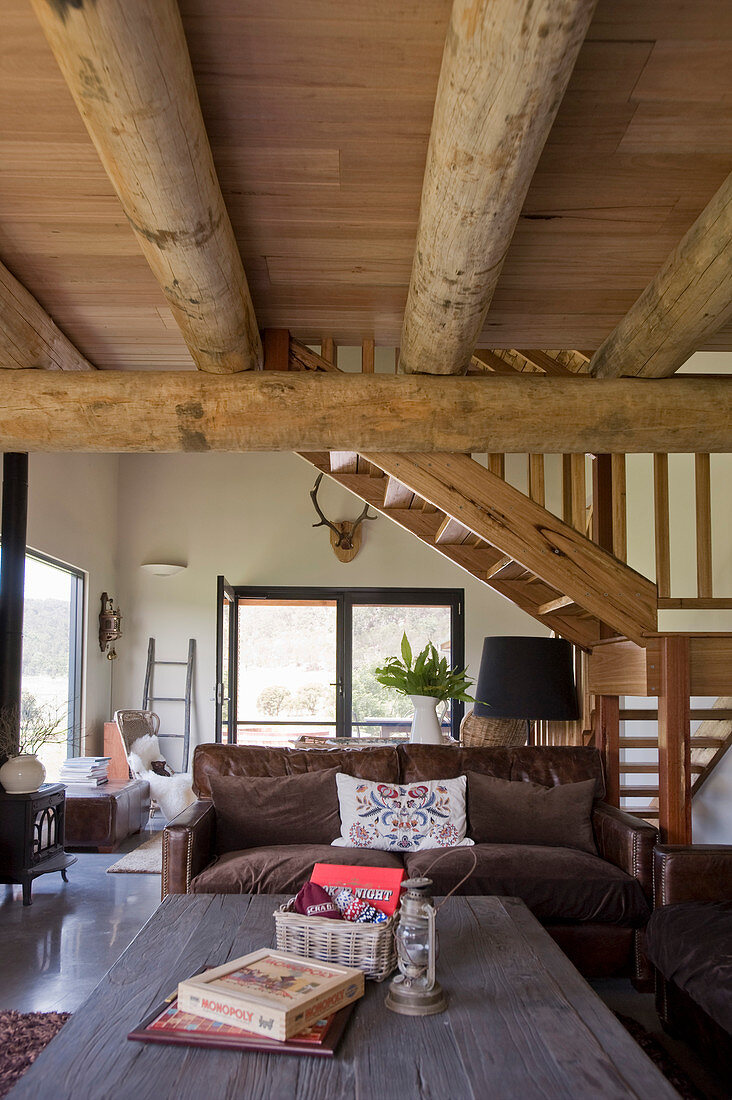 Rustic coffee table and couch in open-plan interior with wood-beamed ceiling