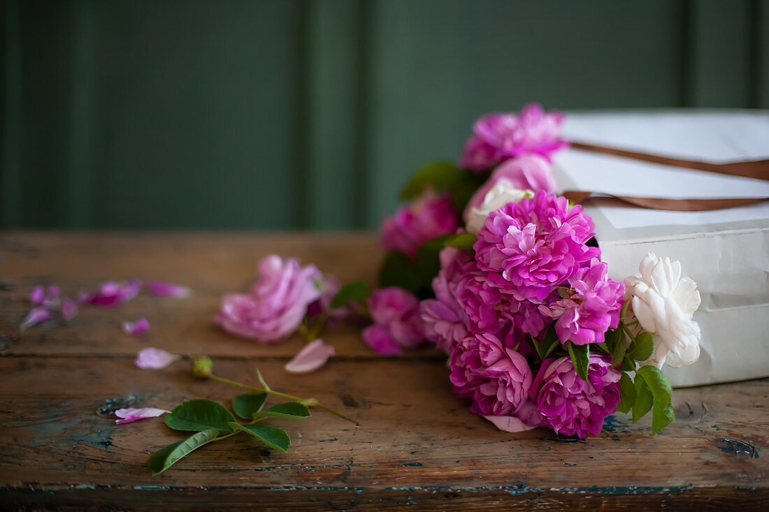 Pinkfarbene Rosen in Papiertüte auf Holztisch