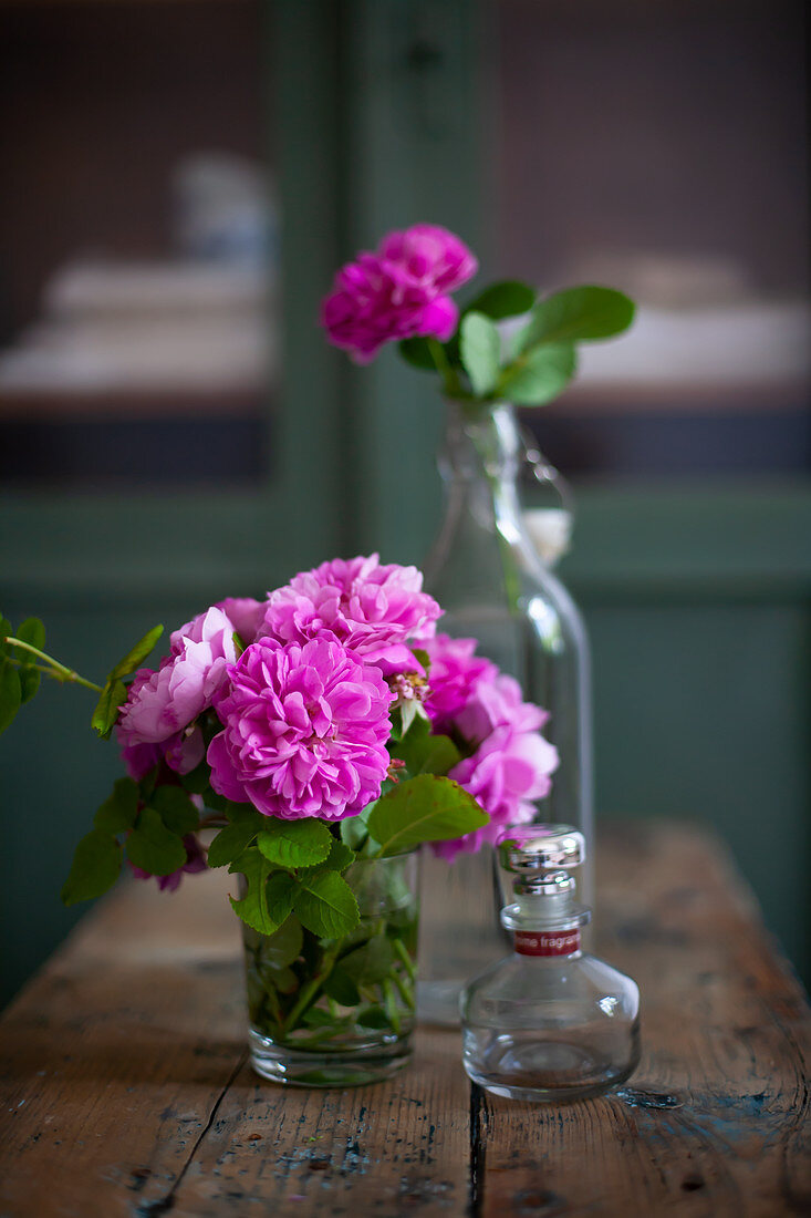 Sträusschen aus pinkfarbenen Rosen im Glas auf Holztisch