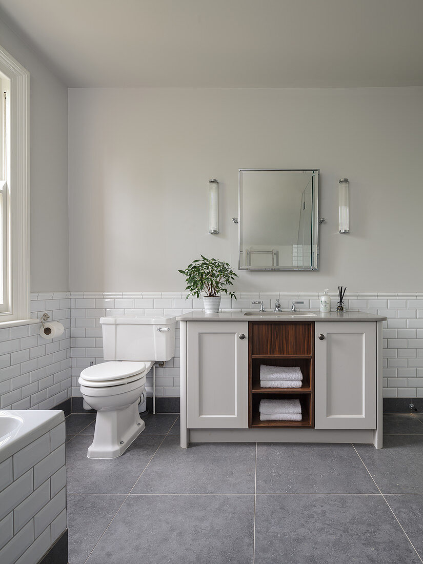 Washstand next to toilet in bathroom in shades of pale grey