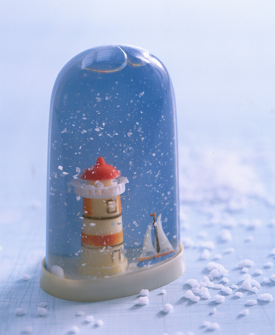 Tall snow globe containing lighthouse and sailing boat