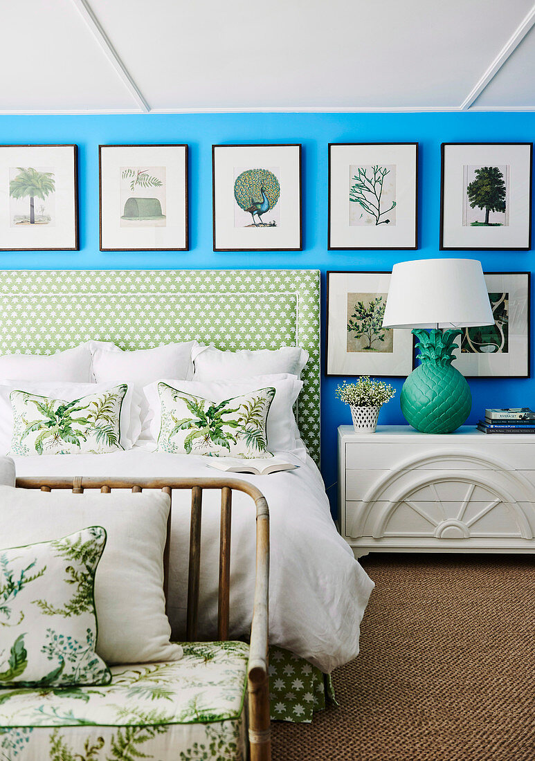 Bildergalerie mit Naturmotiven an leuchtend blauer Wand über Doppelbett