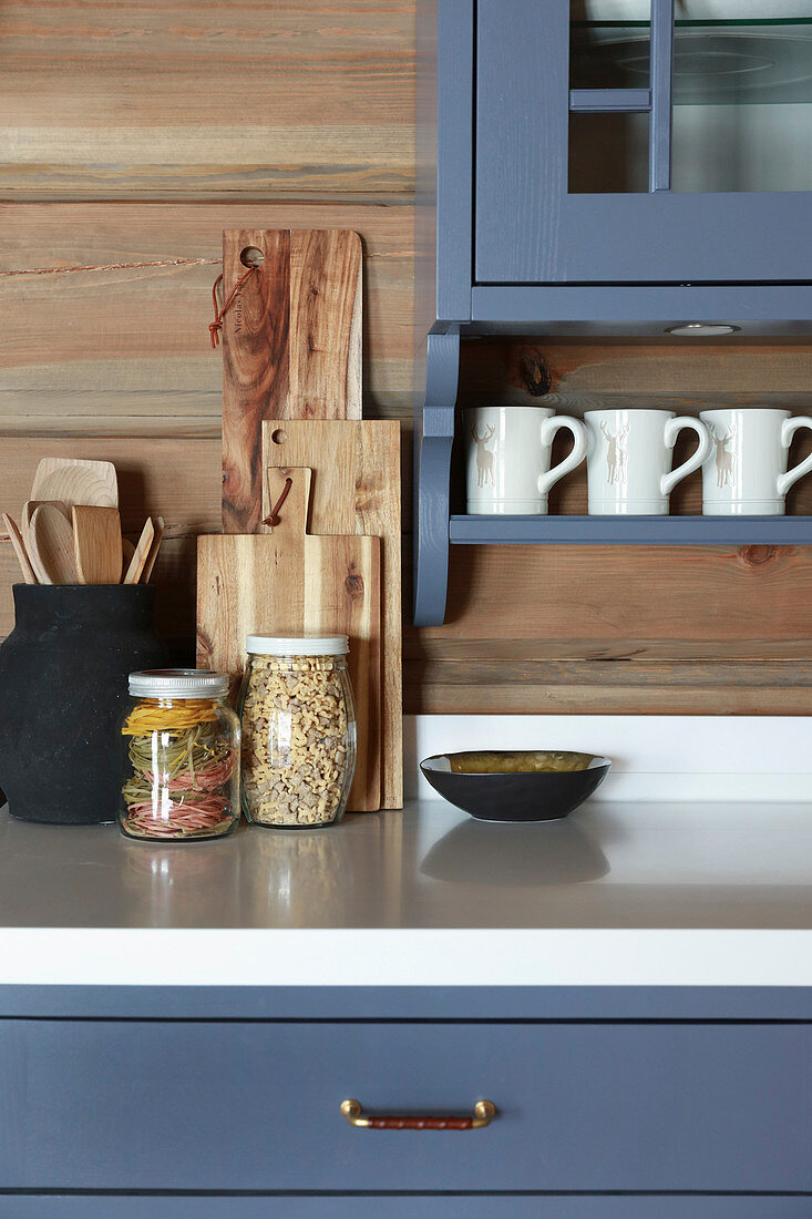 Storage jars and chopping boards in country-house kitchen with blue cupboards