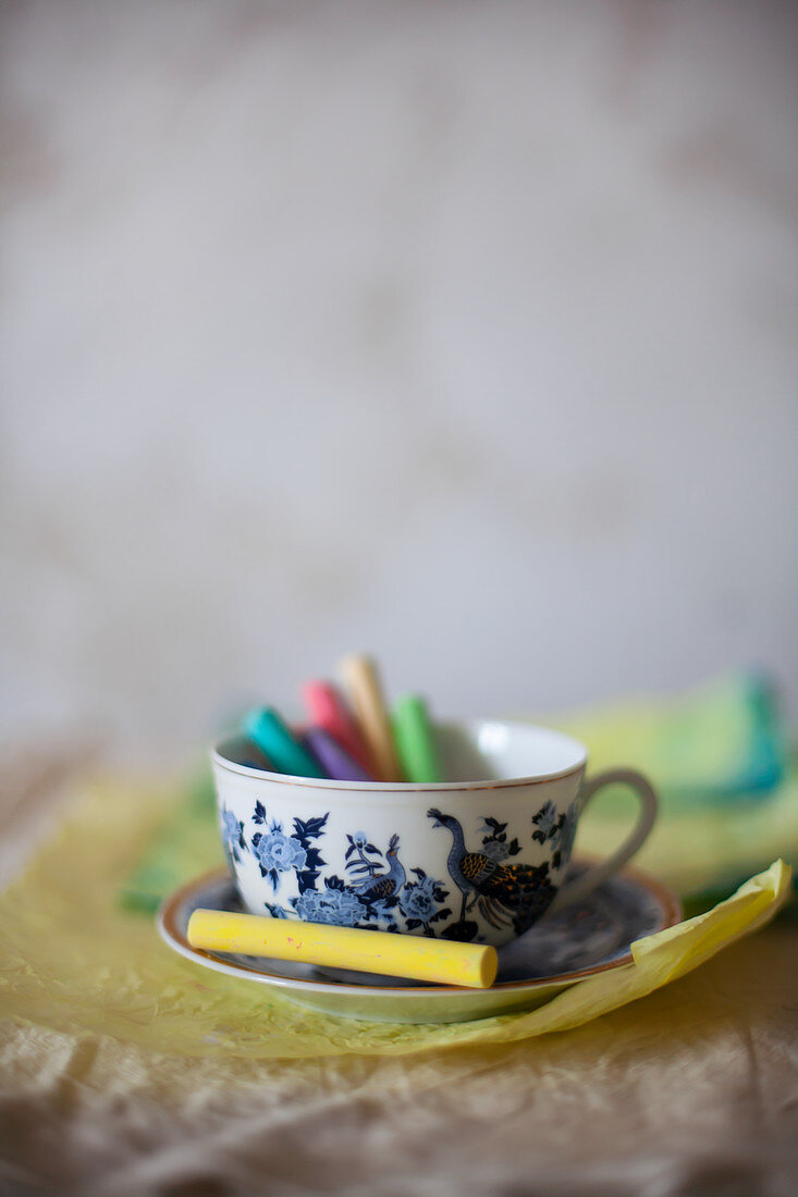 Colourful chalks in cup on crumpled paper