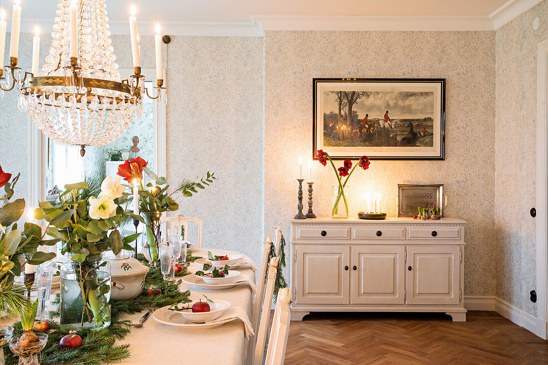 Hunting scene above sideboard and long, festively set dining table in dining room