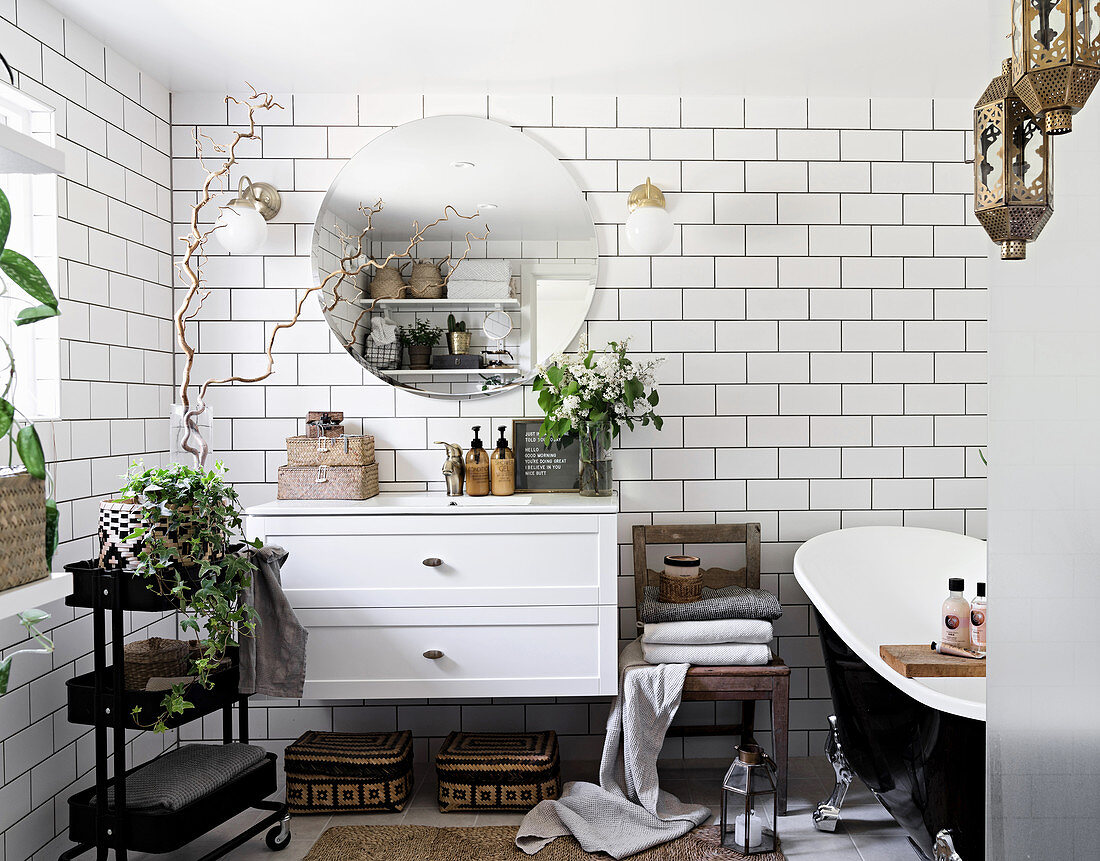 White, Bohemian-style bathroom with subway tiles, floating washstand and free-standing bathtub