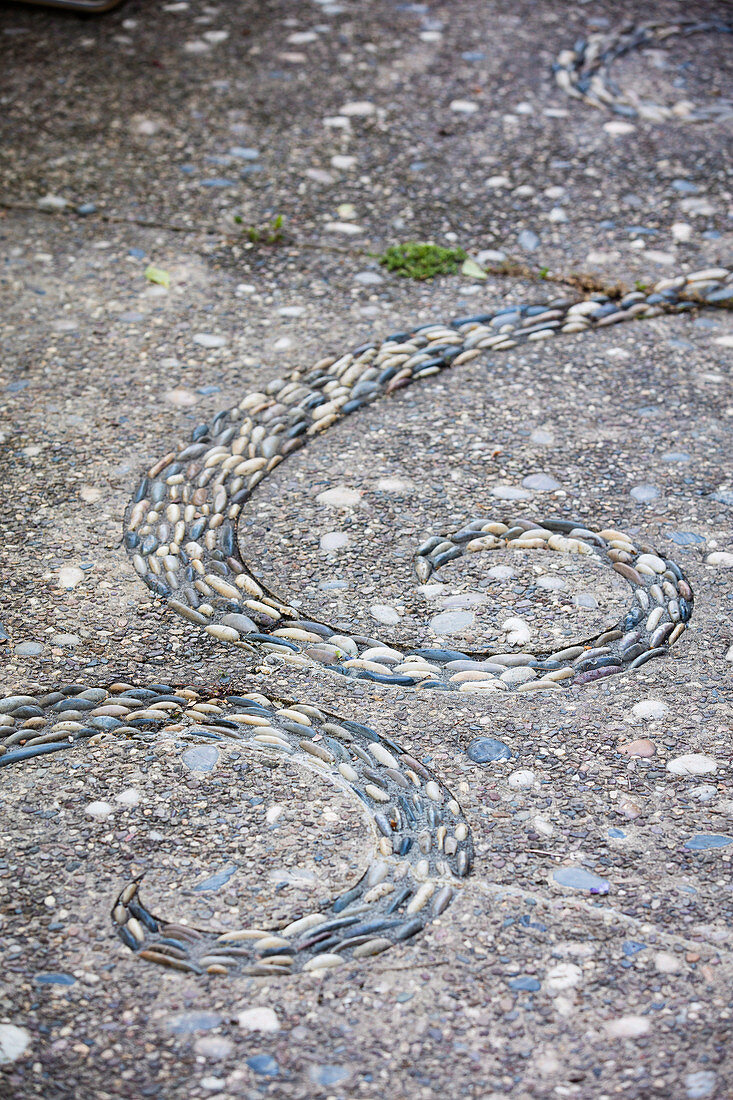 Spirale aus Kies im Terrassenboden aus Waschbeton