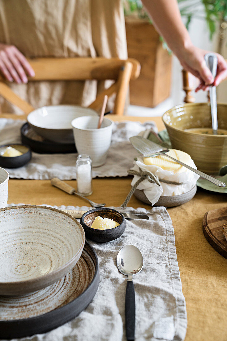 Gedeckter Esstisch mit Keramiktellern, Suppe wird serviert