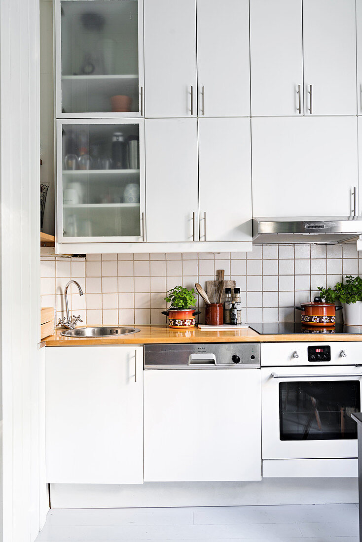 White fitted kitchen with white-tiled splashback