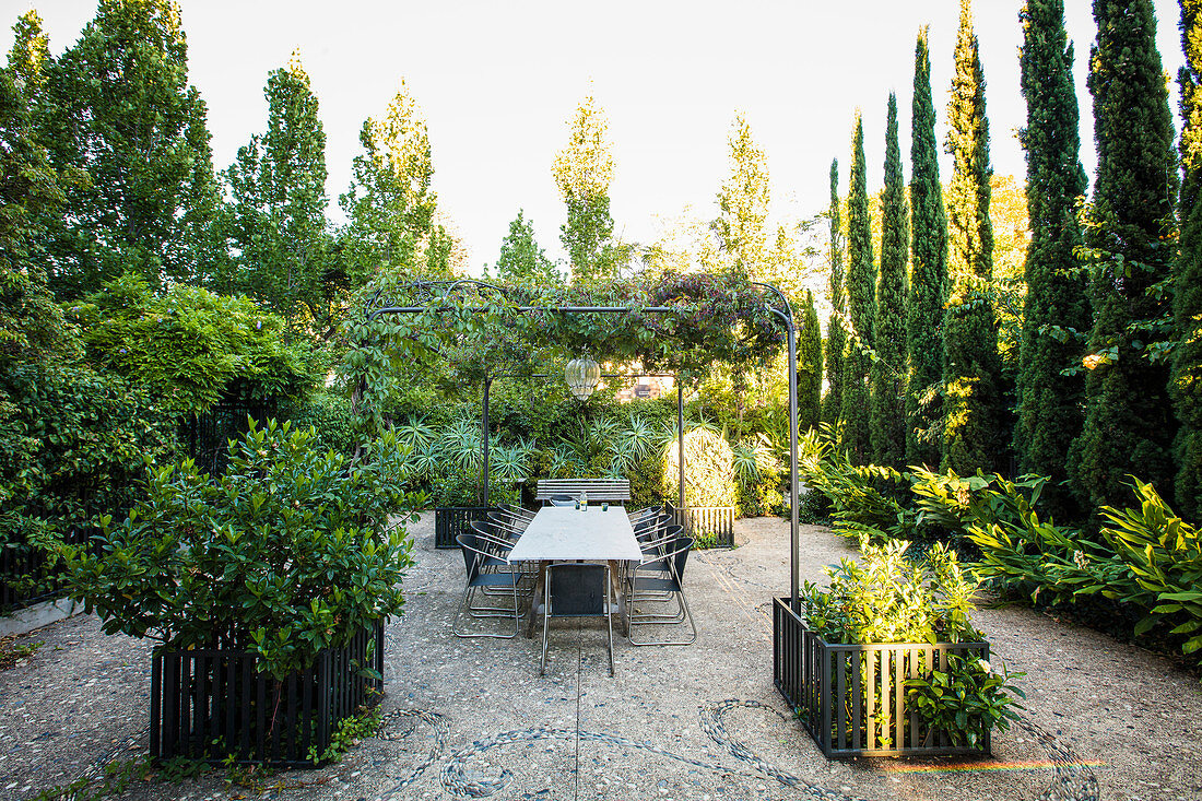 Langer Tisch auf der Terrasse mit Pergola im sommerlichen Garten