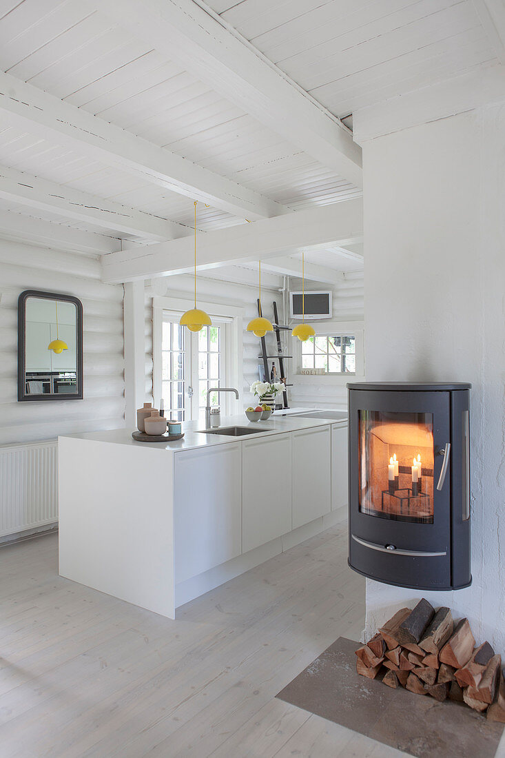 White island counter in kitchen and fireplace in foreground in white-painted log cabin
