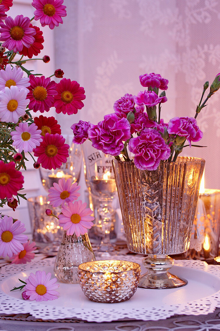 Nelken, Margeriten und Teelichter als romantische Tischdekoration