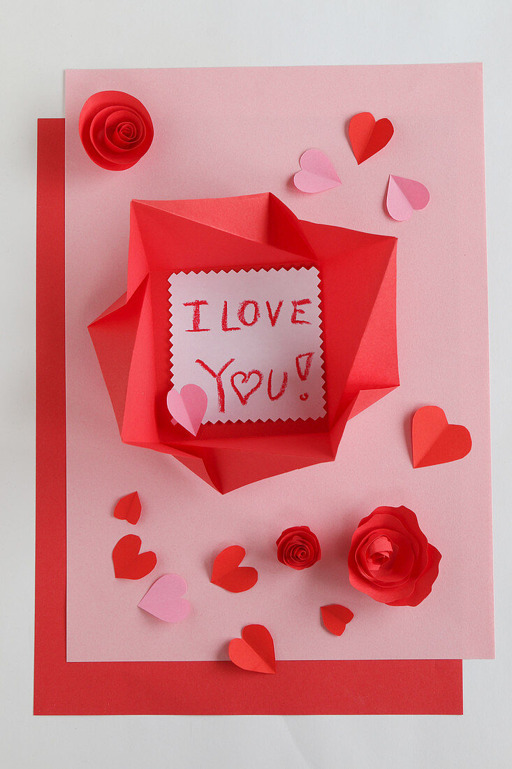 Love note in origami envelope on pink and red paper