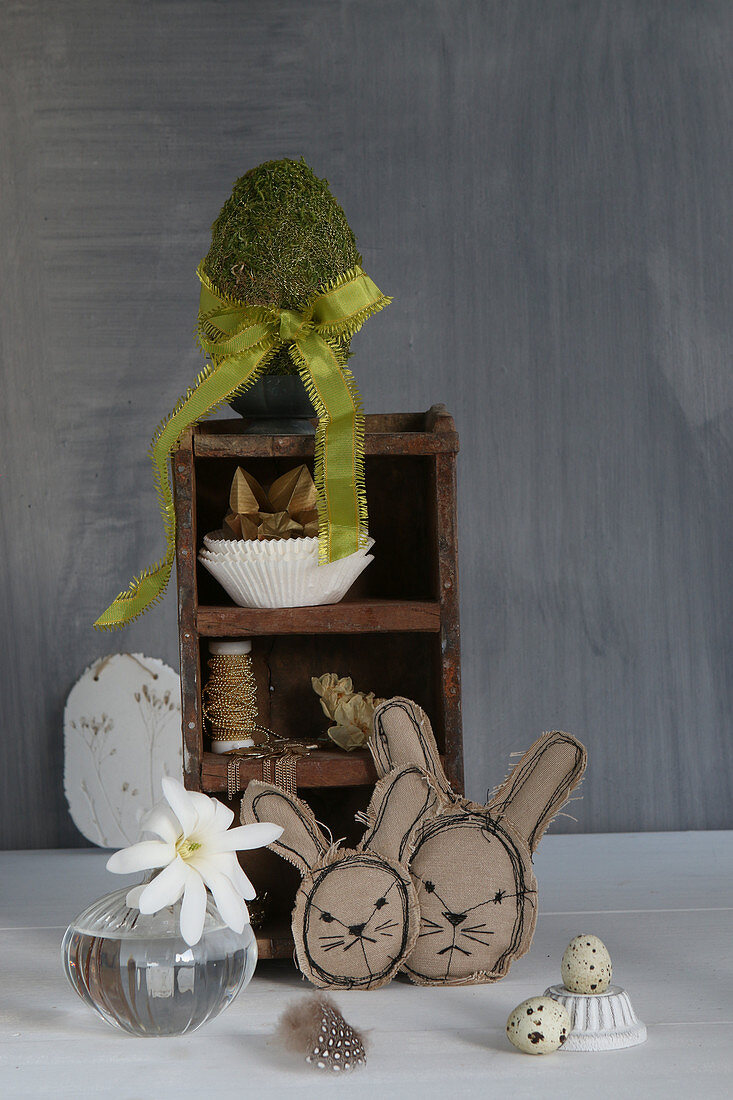 Stitched Easter bunnies in front of ornaments on small set of shelves