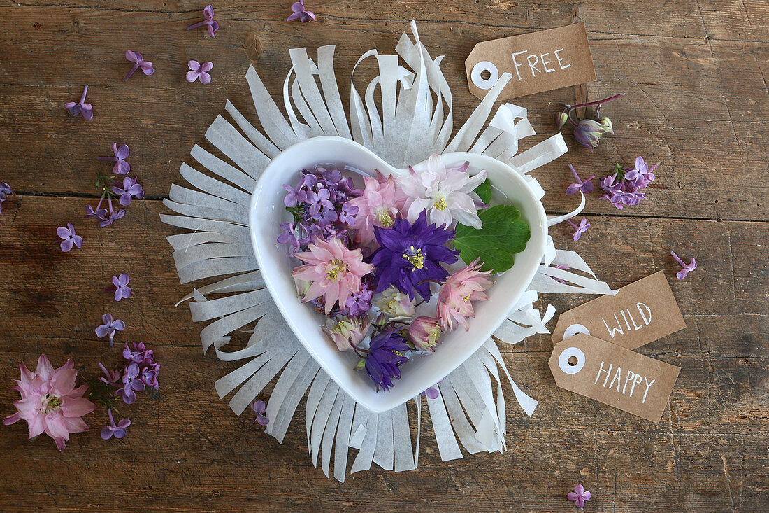 Flowers in heart-shaped bowl on fringed paper mat