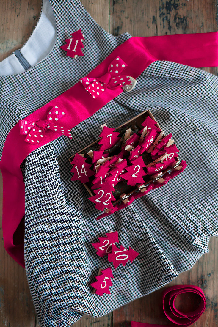 Numbered Christmas trees made from red felt on child's gingham dress