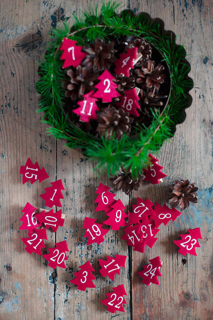 Numbered, red felt Christmas trees in cake tin