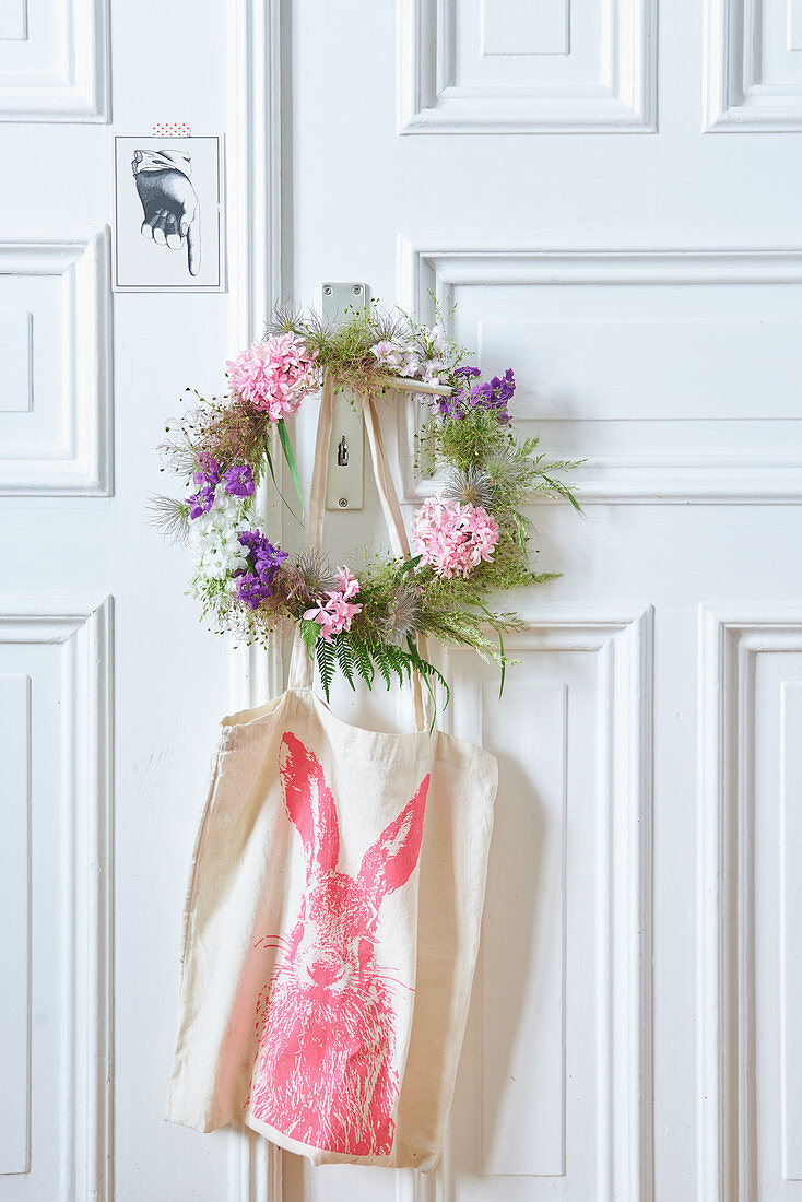 Wreath of flowers and seed heads on door with cloth bag hung below