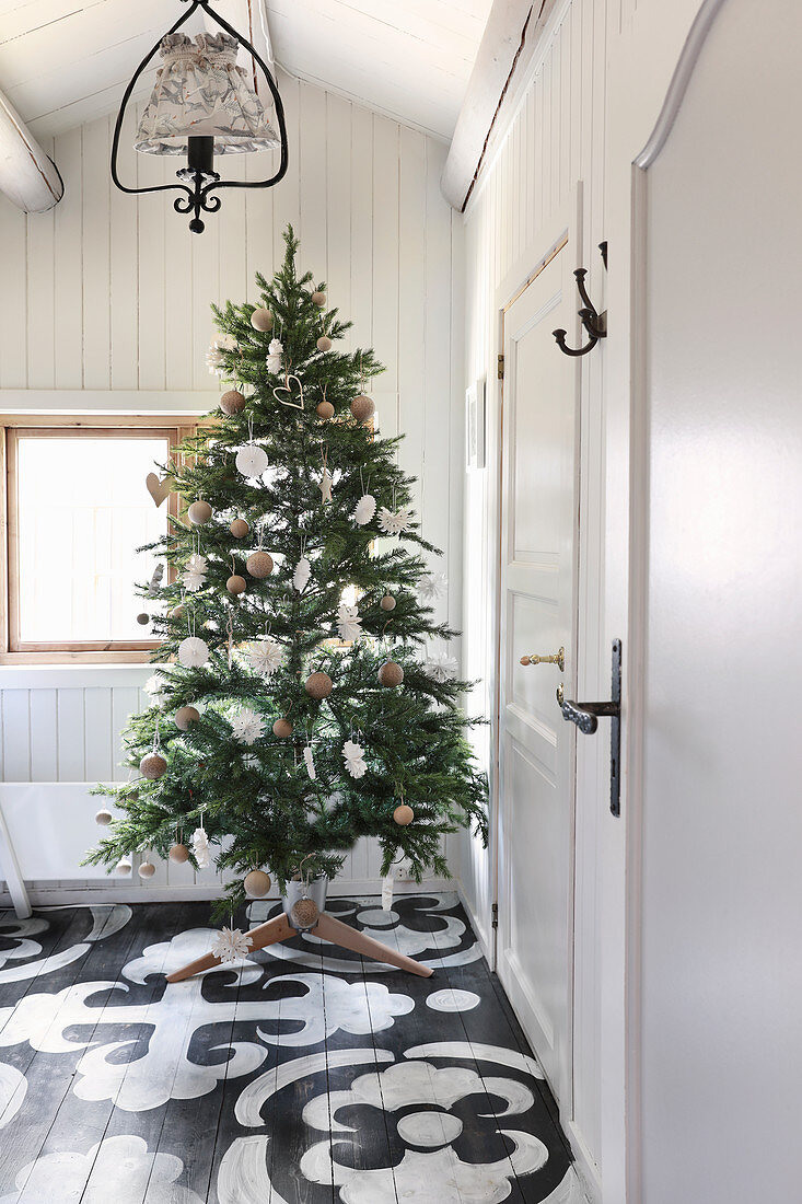 Schlicht geschmückter Weihnachtsbaum auf bemaltem Boden