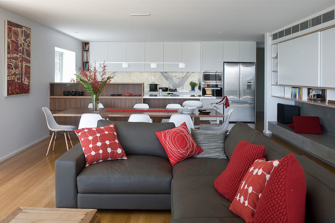 Sofagarnitur mit roten Kissen in elegantem, offenem Wohnraum