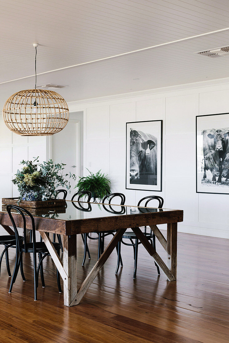 Rustikaler Esstisch mit Stühlen in offenem Wohnraum, an der Wand schwarz-weiße Fotos