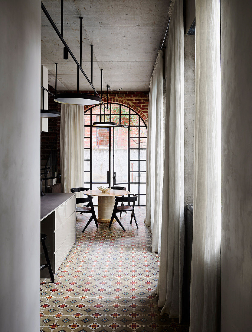 Blick auf Esstisch mit Stühlen in offener Küche, bodenlange Vorhängen und Fliesenboden
