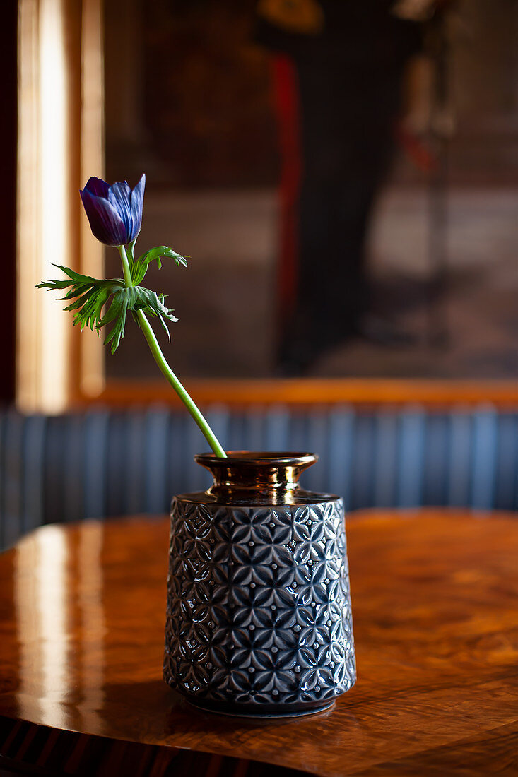 Blaue Anemone in einer Vase mit Relief auf einem Holztisch