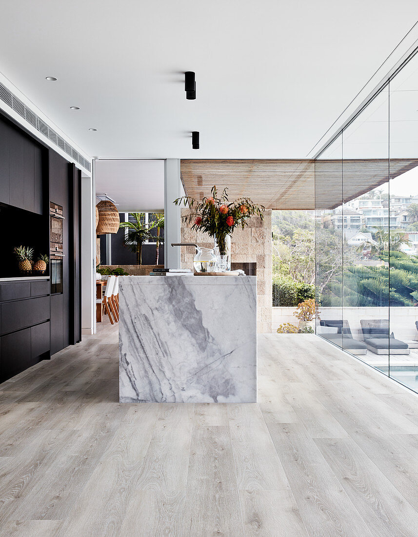 Kücheninsel aus Marmor in offener Küche mit Holzboden und Glasfront