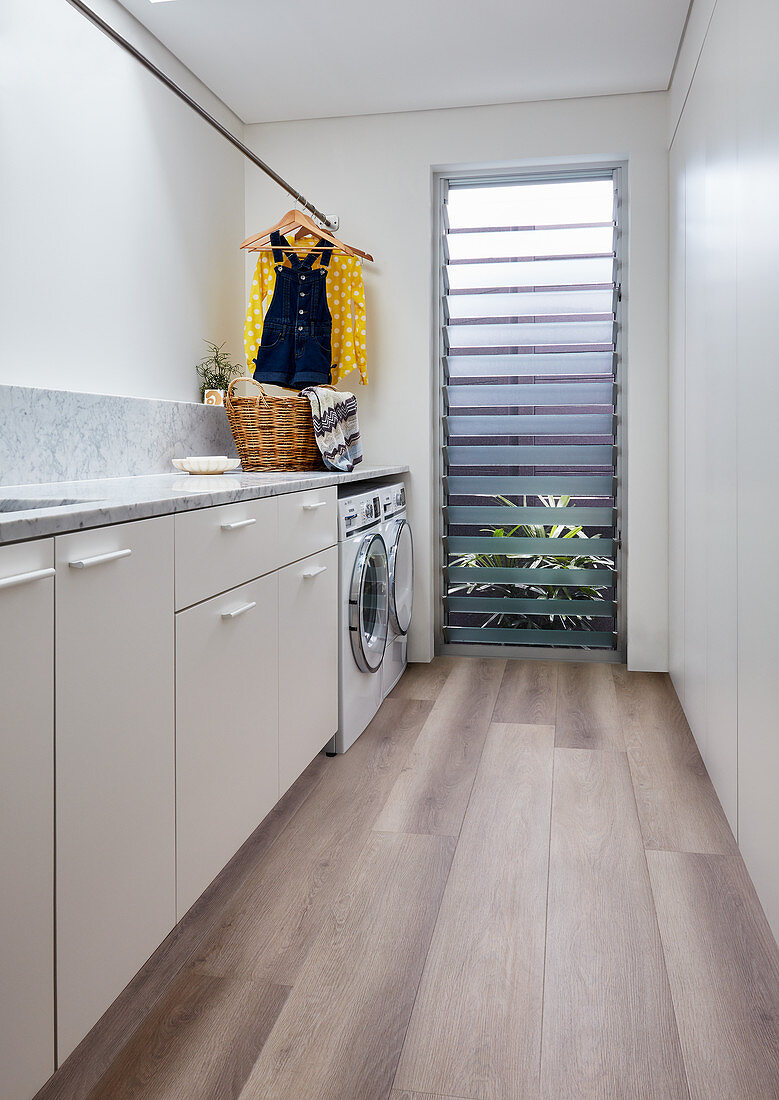 Modern laundry room with wooden floor and louvre window
