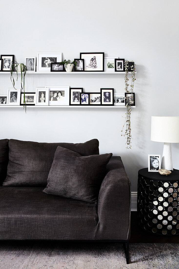 Pictures and plants on two picture ledges above dark grey sofa