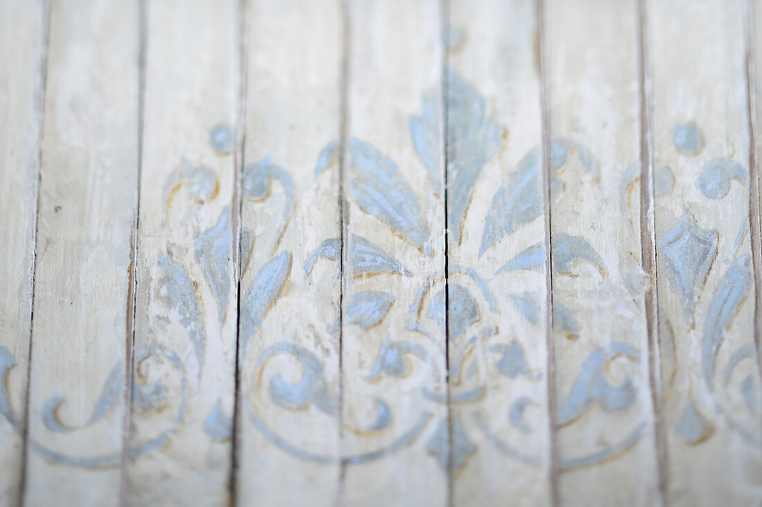 Wooden surface painted with ornate pale blue pattern