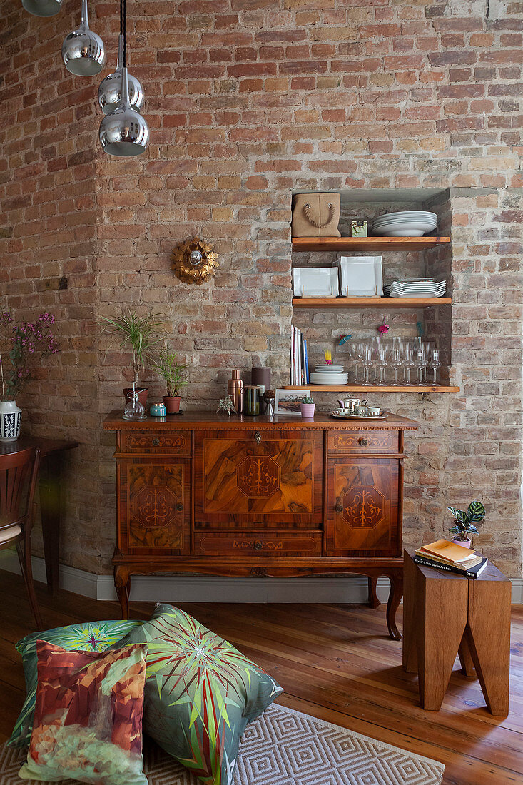 Antique sideboard against brick wall with shelves in niche