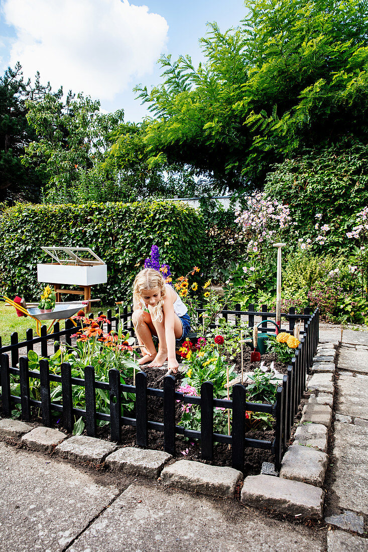 Mädchen im eingezäunten Mini-Garten