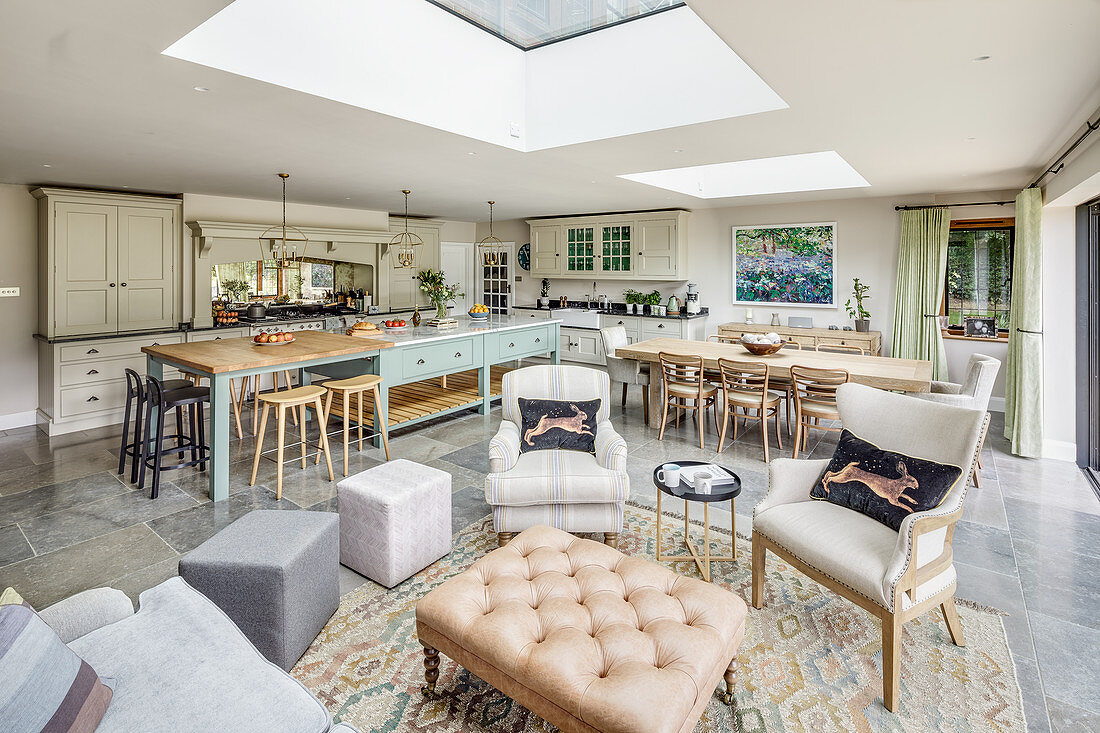 Country-house kitchen, dining and seating areas below skylights in open-plan interior