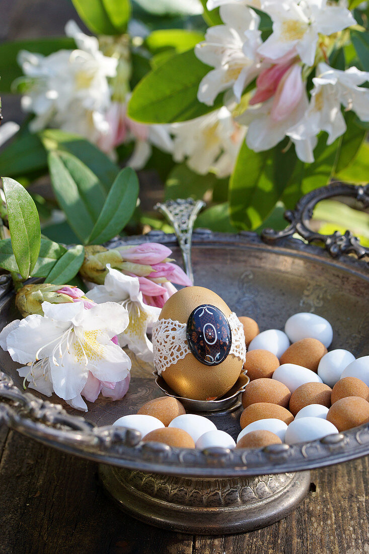 Ei mit Spitze in Silberschale mit Rhododendron-Blüten und Marzipaneiern