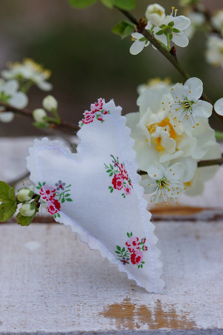 Hand-sewn fabric heart in front of narcissus and cherry blossom