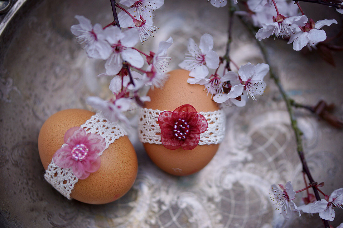 Ostereier in Spitzenband mit Blüten der essbaren Blutpflaume