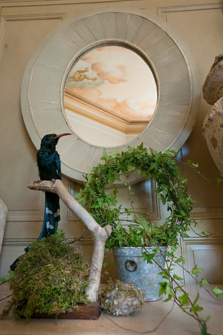 Stuffed bird and wreath of ivy below round mirror