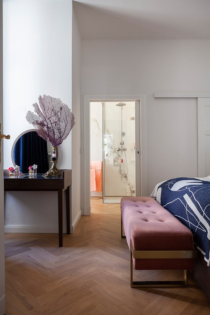Elegante Polsterbank vorm Bett im Schlafzimmer mit Bad