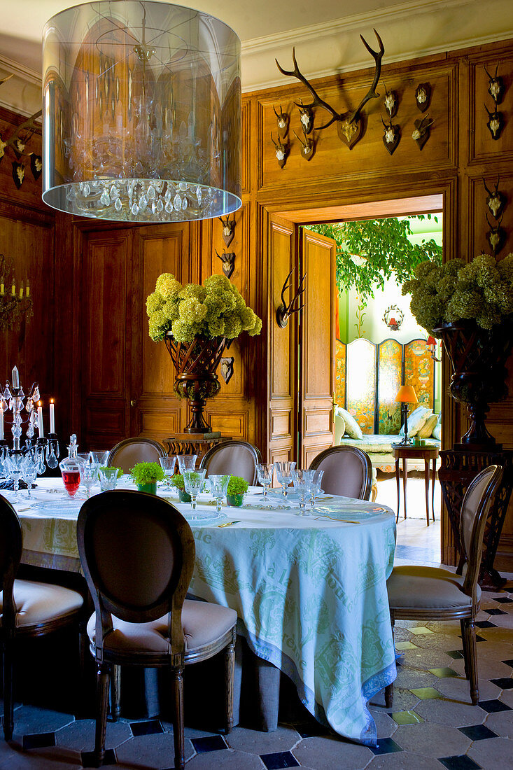 Flower arrangements, wood-panelled walls and hunting trophies in stylish dining room