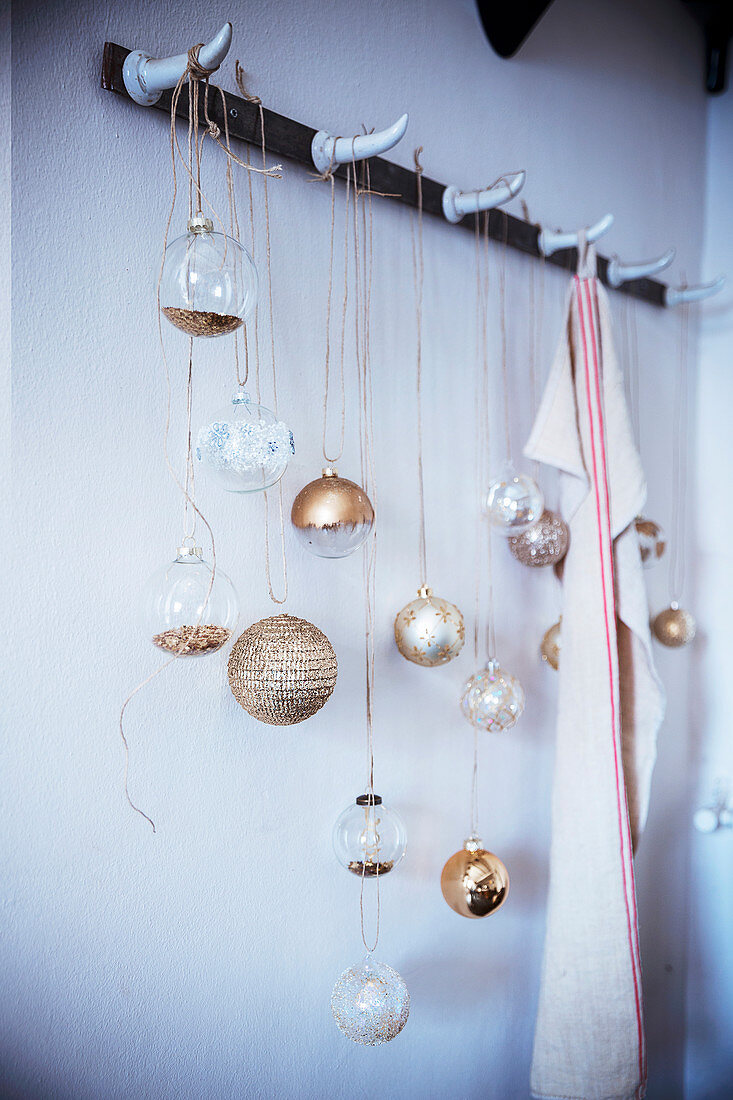 Festive arrangement of Christmas-tree baubles hung from coat rack