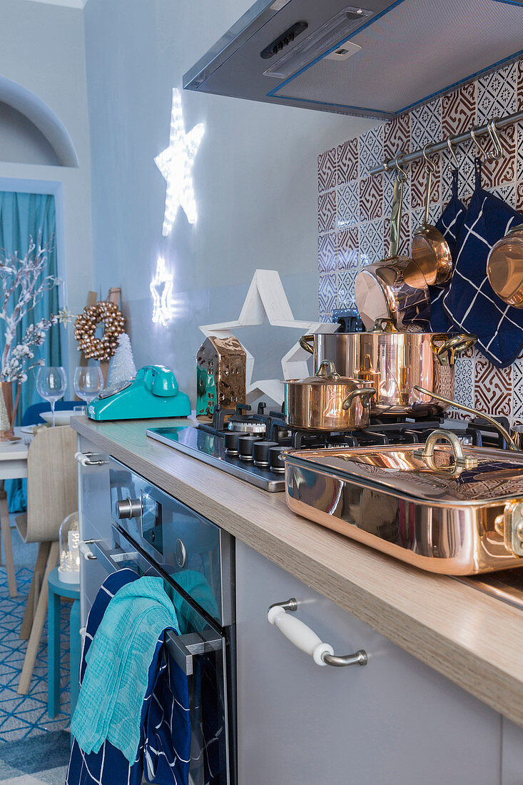 Kupfergeschirr auf Herd in blauer weihnachtlich dekorierter Küche