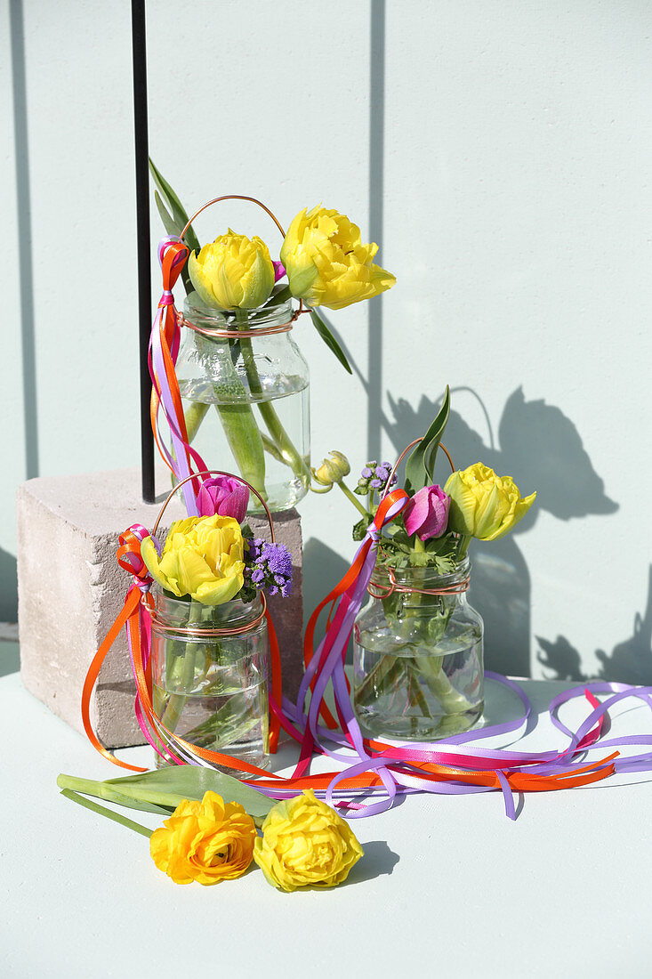 Gefüllte Tulpen in Schraubgläsern mit bunten Stoffbändern