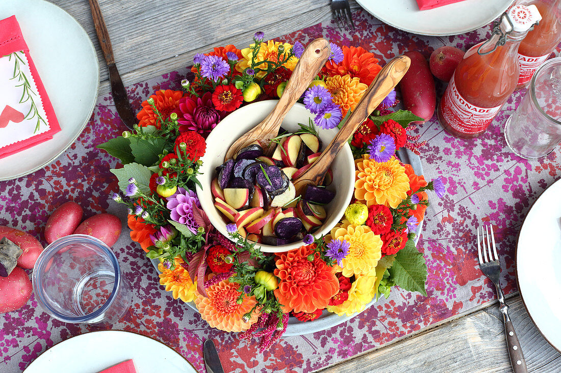 Colourful potato salad in wreath of flowers on set table