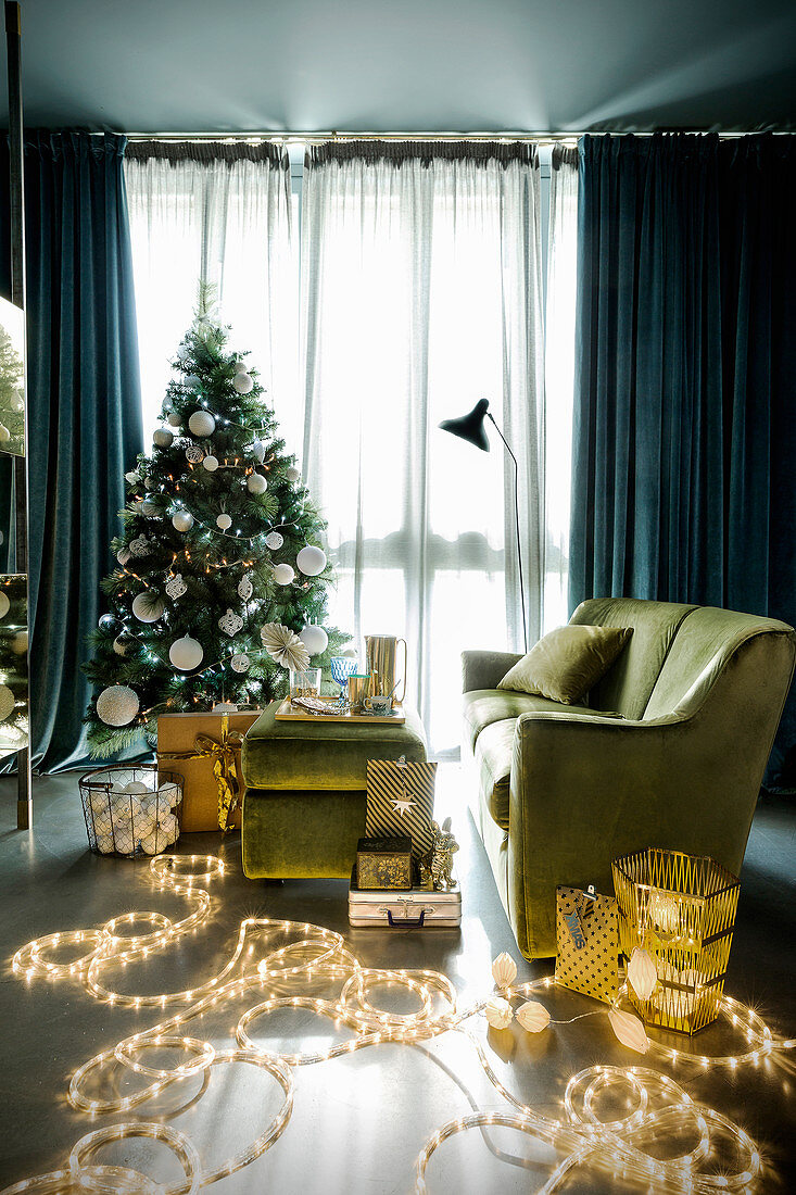 Wohnzimmer in Grün weihnachtlich dekoriert mit Lichterketten und Weihnachtsbaum