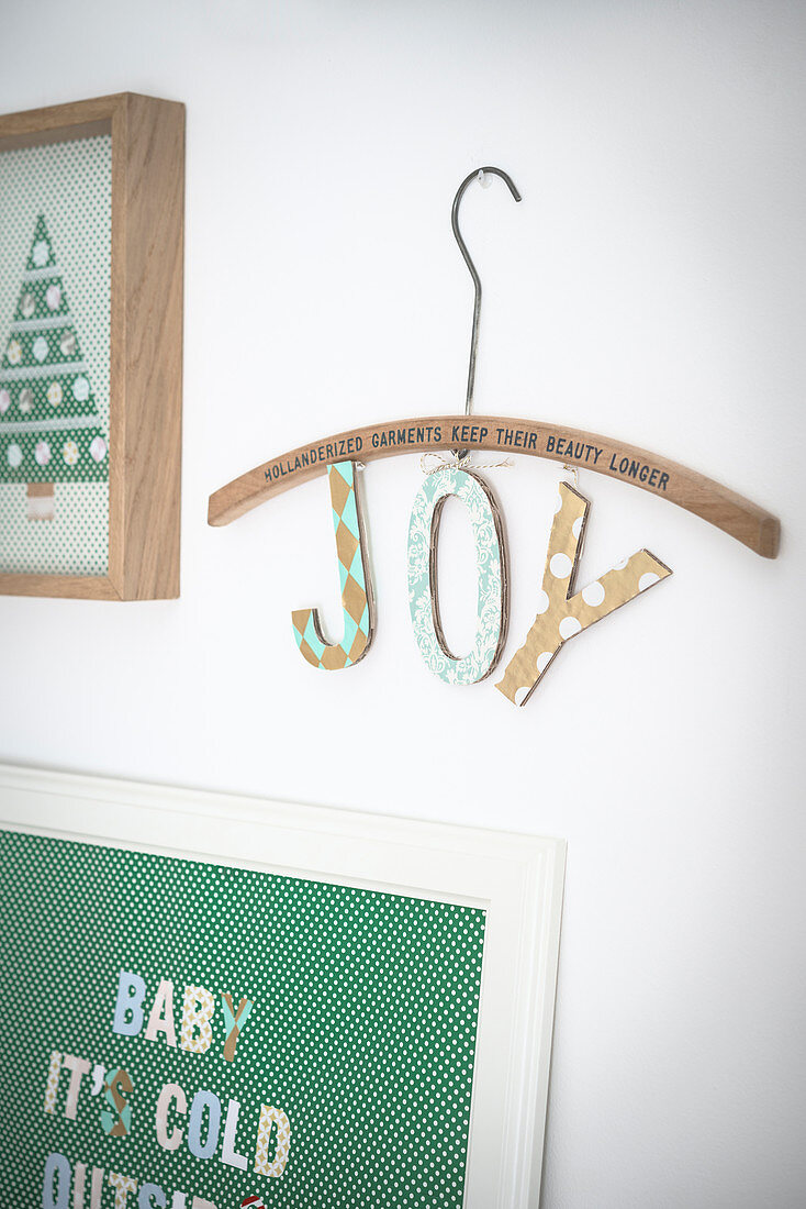 Zwei Collagen und ein Holzbügel mit Schriftzug 'Joy' als weihnachtliche Wandekoration
