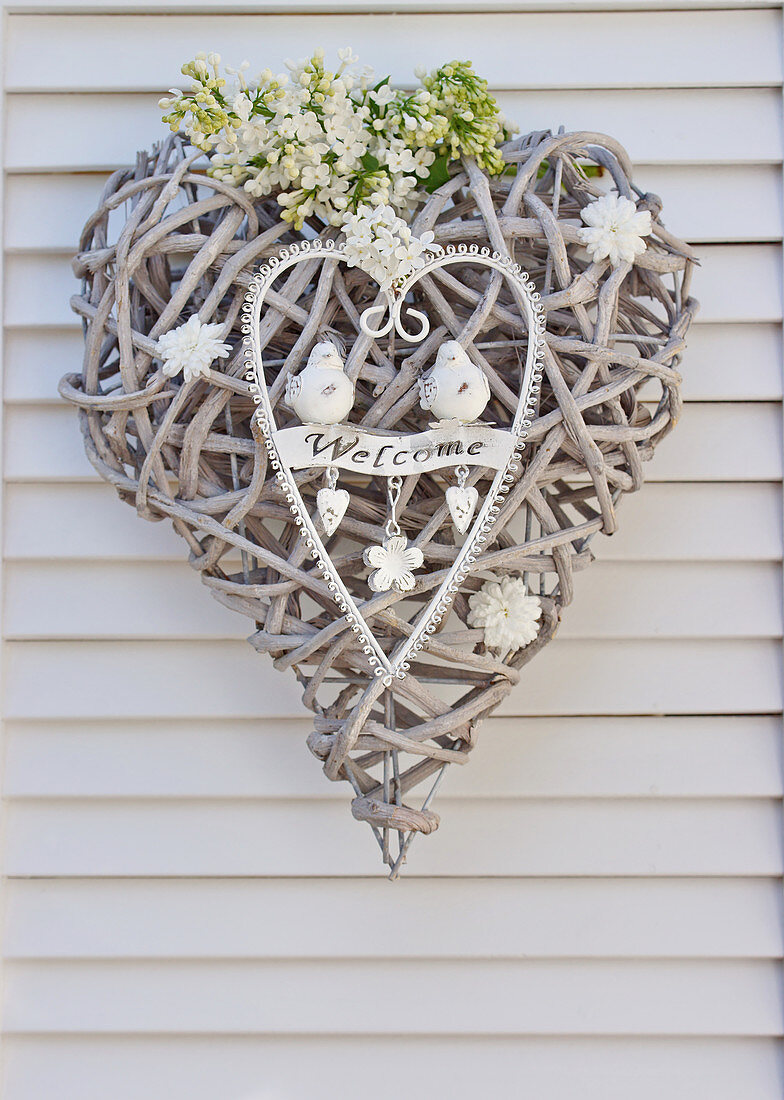 Welcome sign made of woven-vine heart with lilac flowers and metal heart