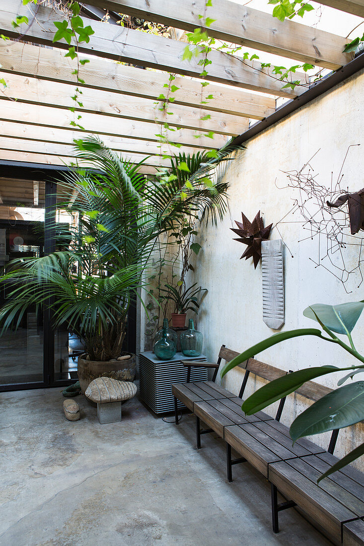 Sitzbank und Topfpflanzen auf Terrasse mit Betonboden